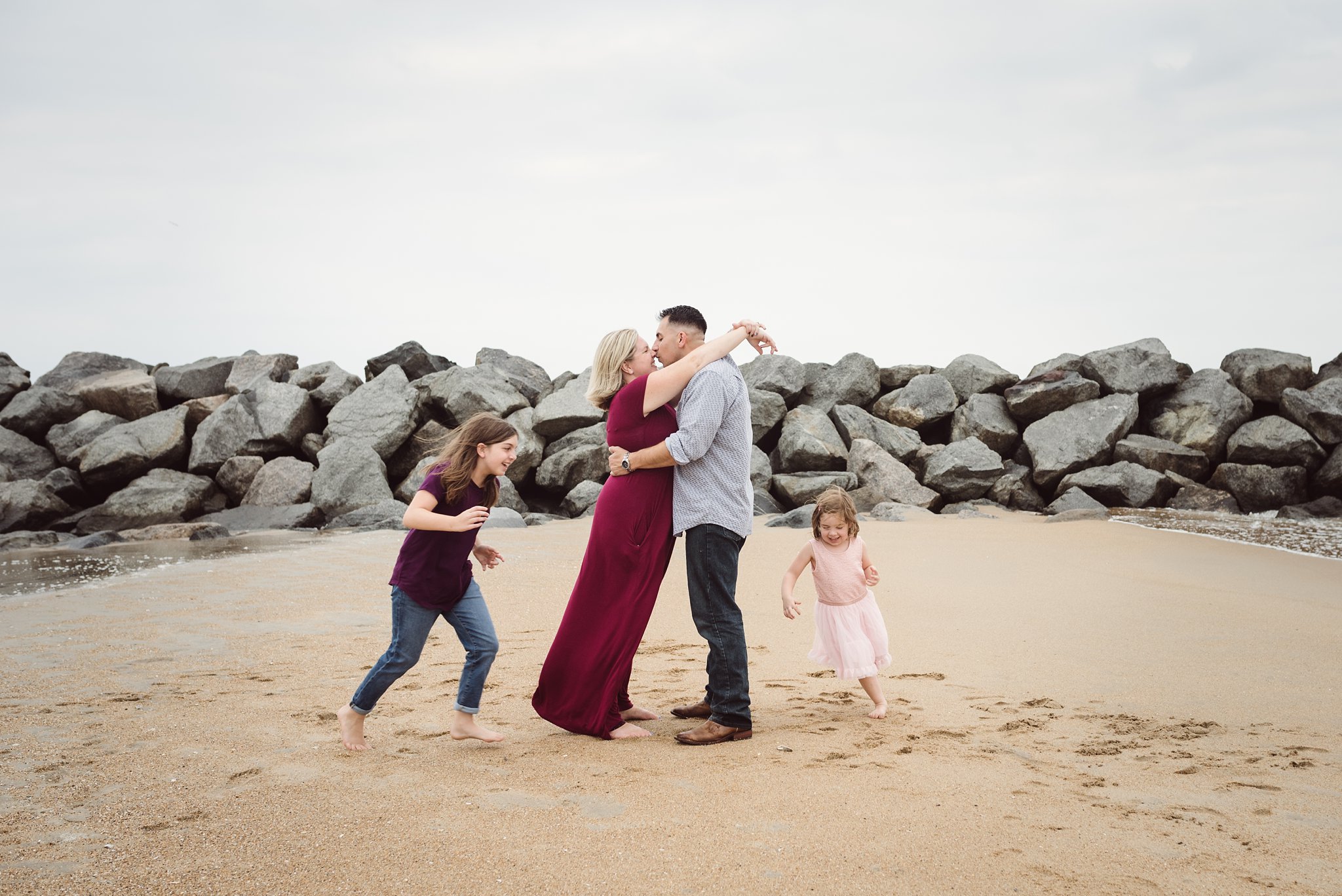 family photo on the beach, girls running around mom and dad on the beach in Virginia Beach VA