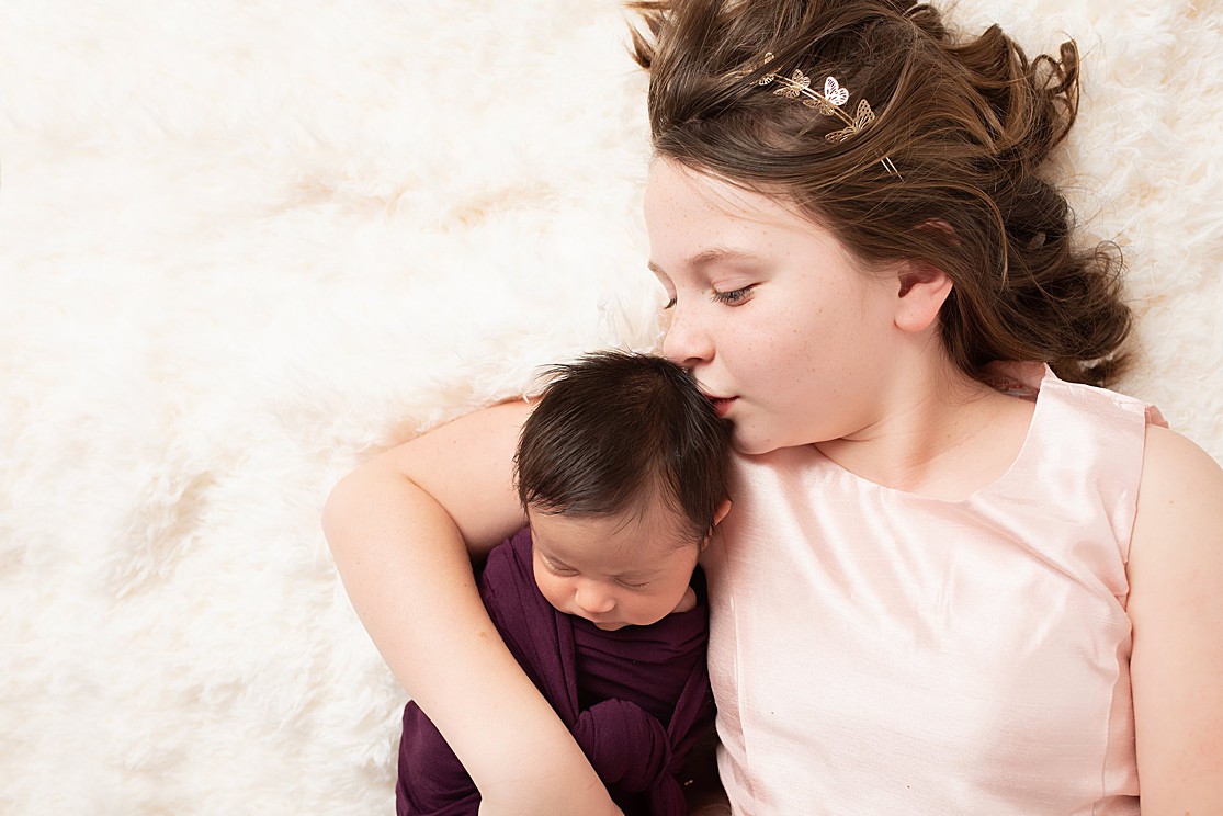 newborn girl and older sister, in home newborn photography, newborn baby girl in purple and sister kissing her head