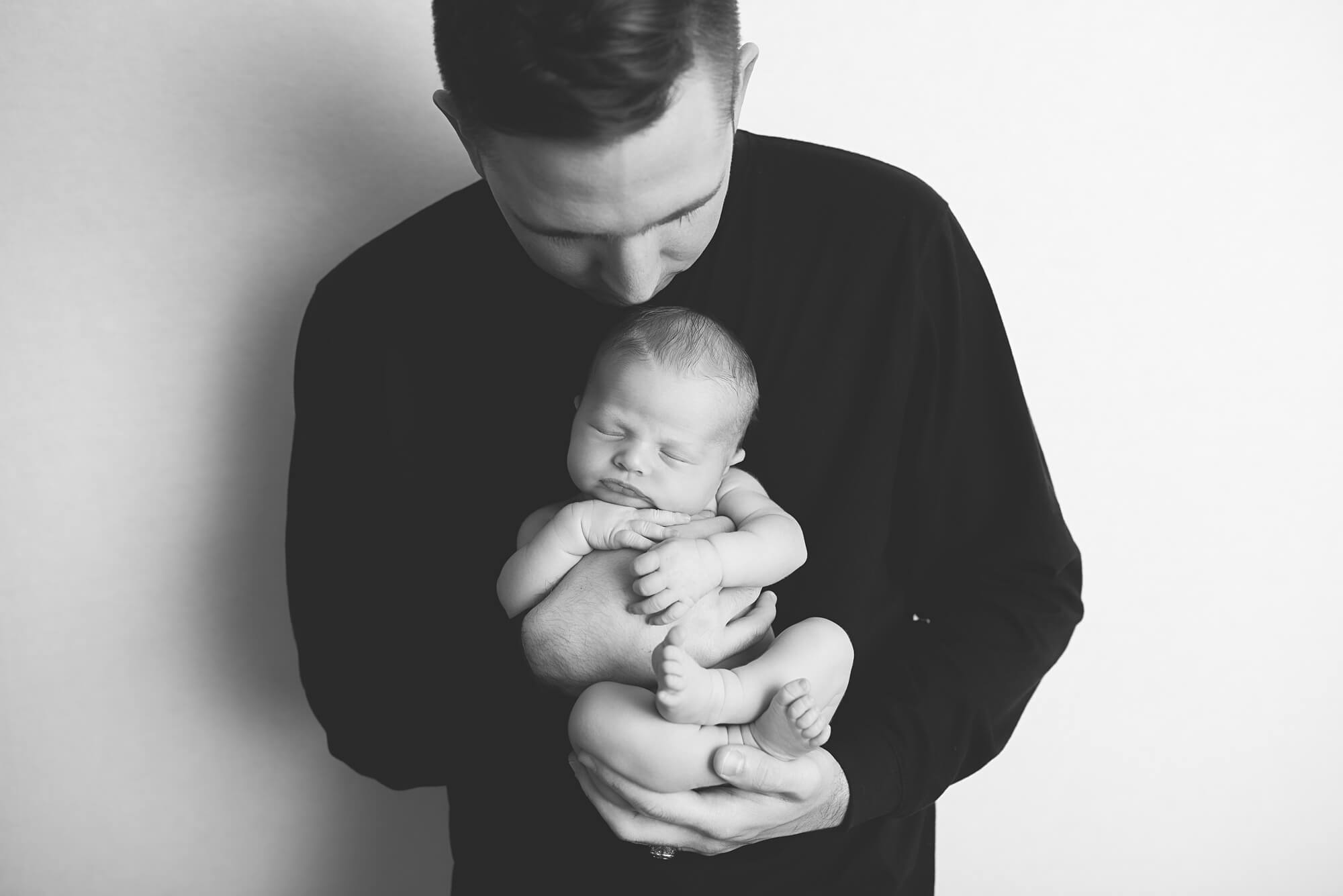 black and white photo of dad holding newborn baby, womb service