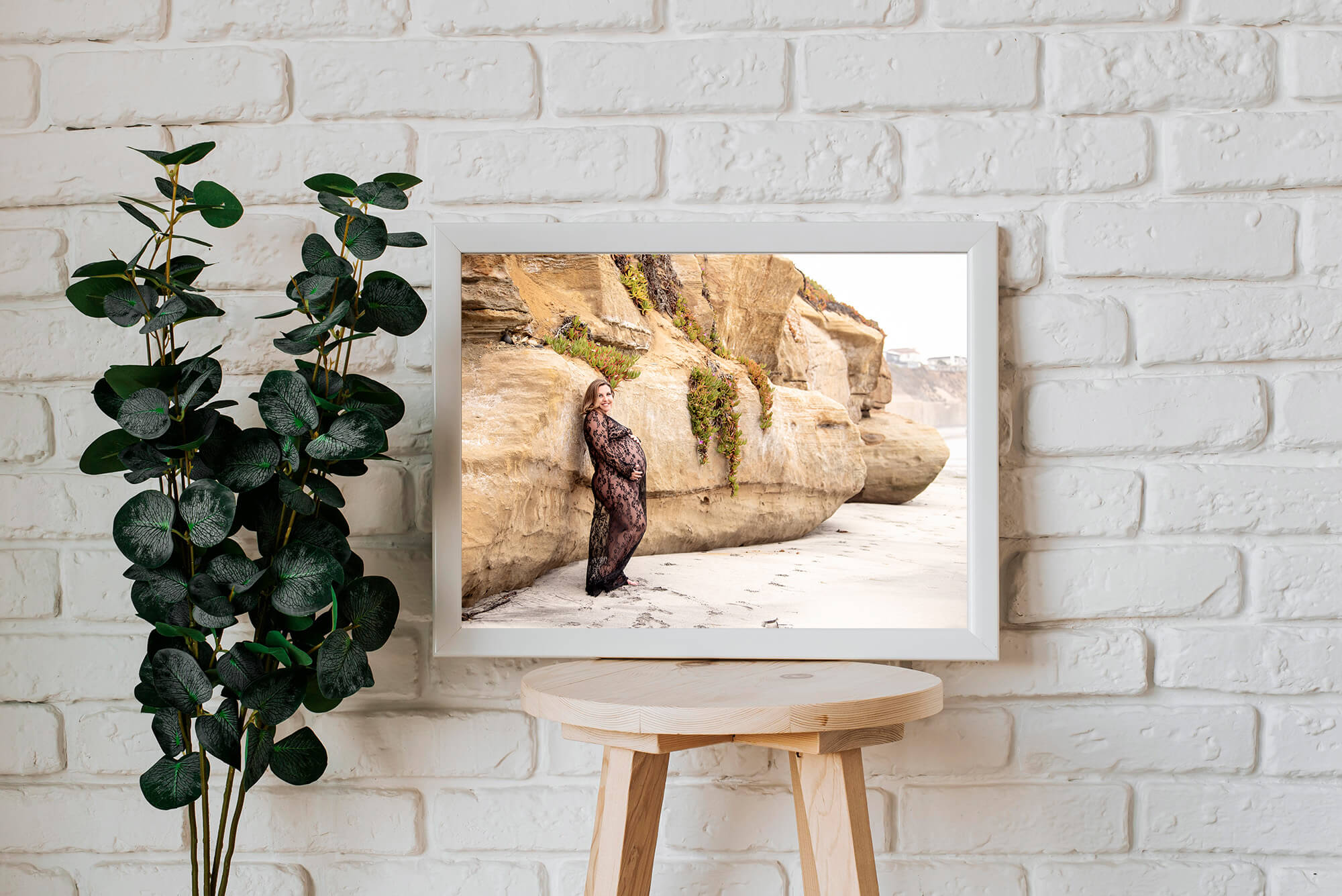 image of a framed photo taken by San Diego maternity photographer Lauren V Photography, pregnant female leaning against the bottom of a cliff on the beach