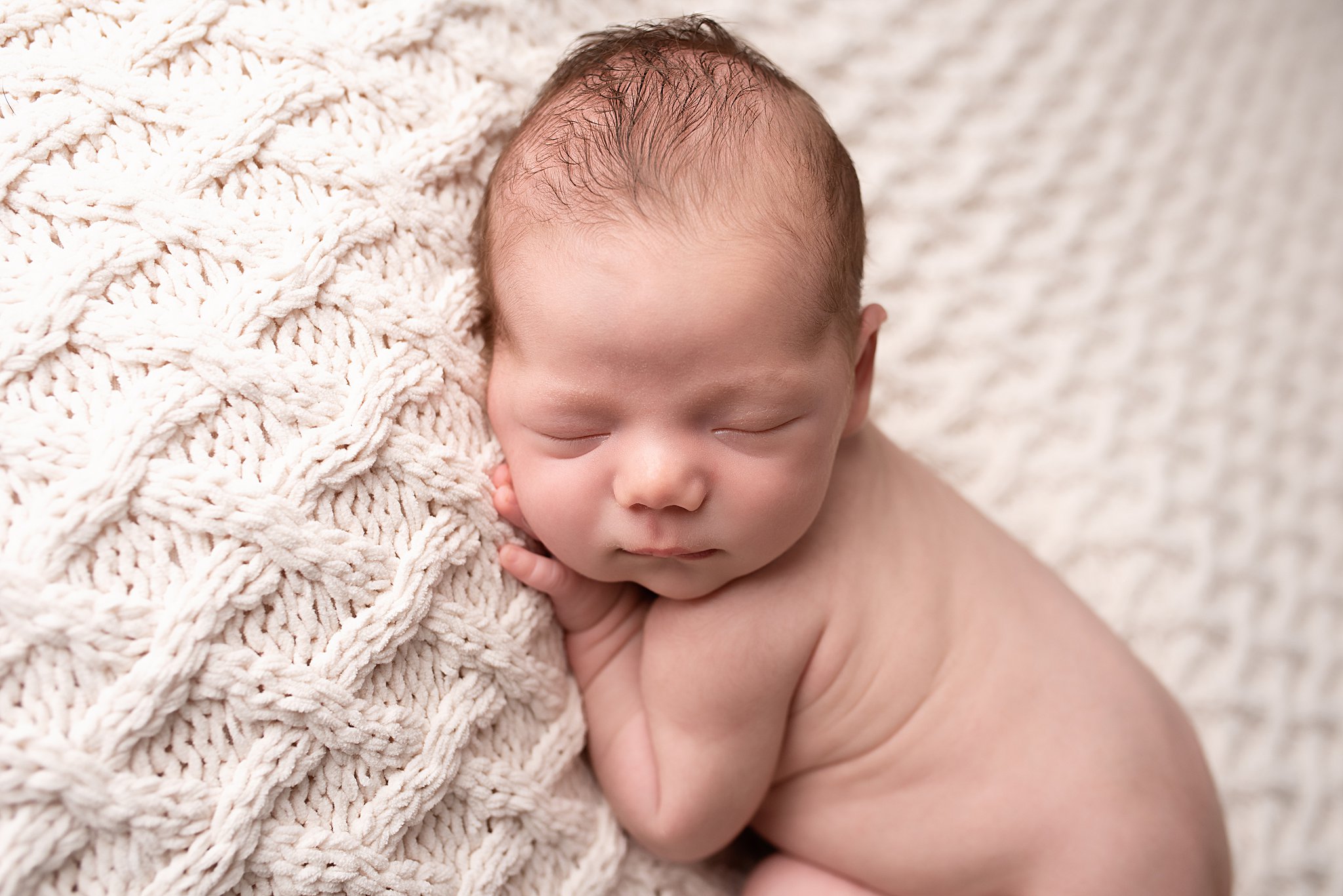 A newborn baby sleeps on a woven blanket Blossom Baby Oceanside